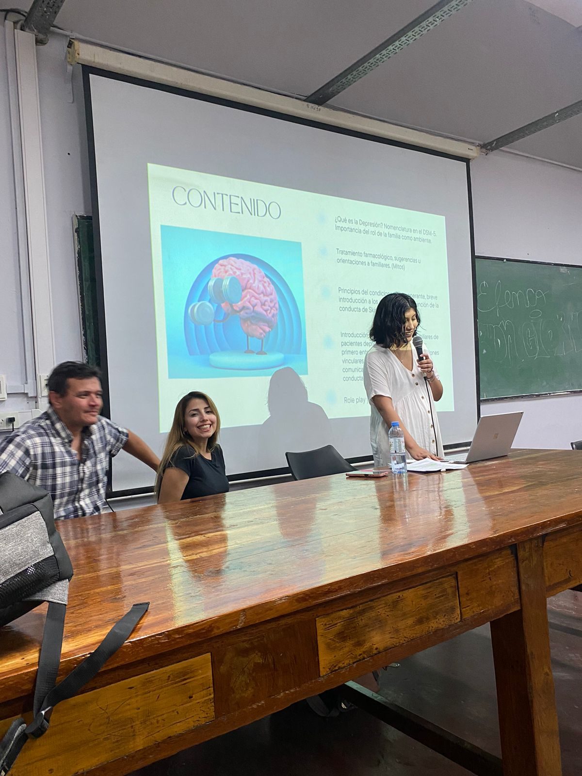 Andrea Garzon presenting with a microphone at the University of Buenos Aires.