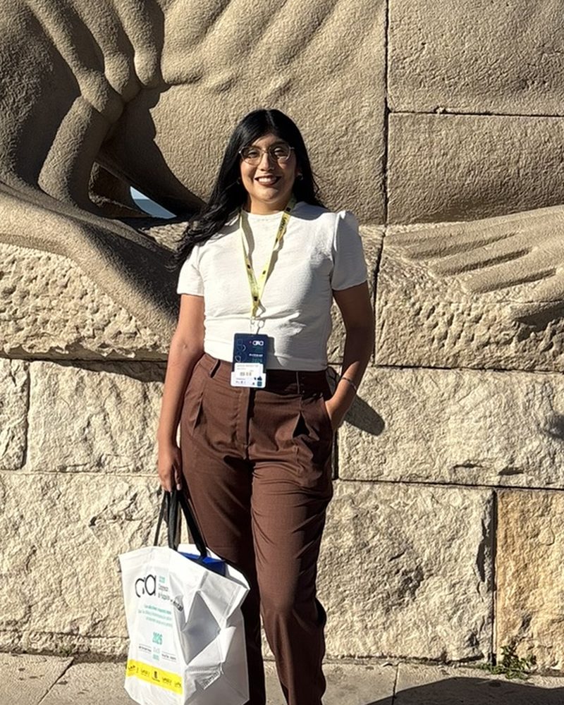 Andrea Garzon con la credencial de un congreso, frente a una escultura de la rambla de Mar del Plata.