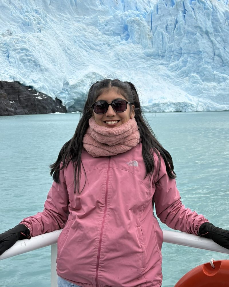 Andrea Garzon sonríe en la proa de un barco, frente a un glaciar.