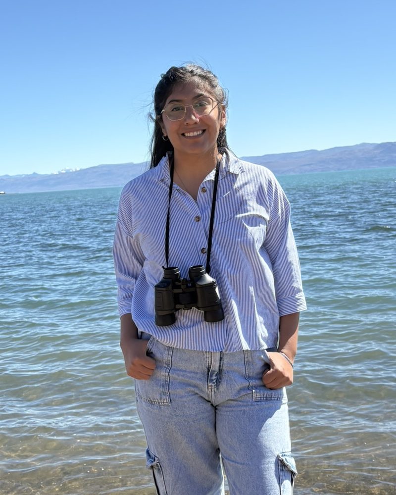 Andrea Garzon sonríe a orillas de un lago, con montañas de fondo.